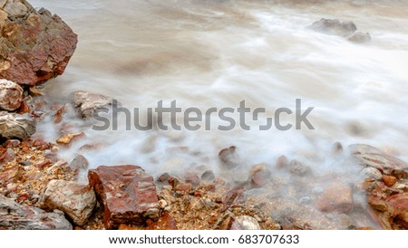 Landscape long exposure of beach in malaysia. The waves hit the rocks on the beach. 