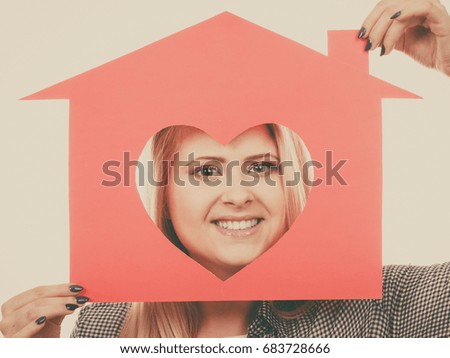Charity, real estate and family home concept - Happy smiling teen girl holding red paper house with heart shape, toned image