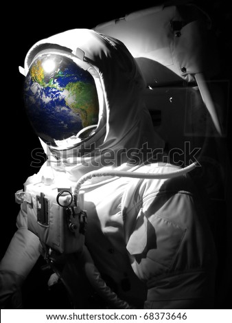 A complete astronaut space suit with a reflection of the earth reflecting in the helmet.  Selective color.  Earth photo courtesy of NASA.