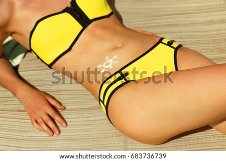 Portrait of gorgeous woman in bikini with the drawn sun on a stomach at beach