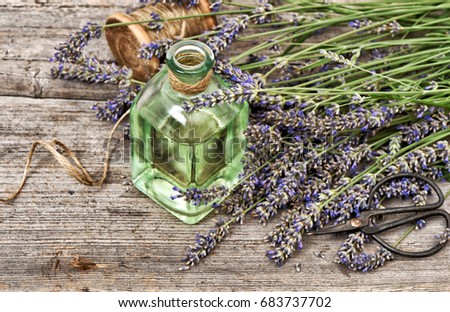 Lavender oil with fresh flowers on wooden background. Vintage style toned picture