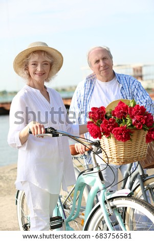 Happy senior couple with their bicycles near river