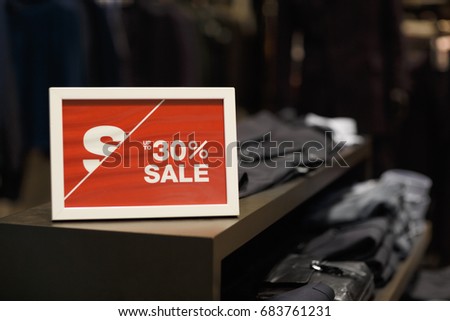 Shopping mall, sales - big poster showing discount and sale in clothing store, selective focus, nobody
