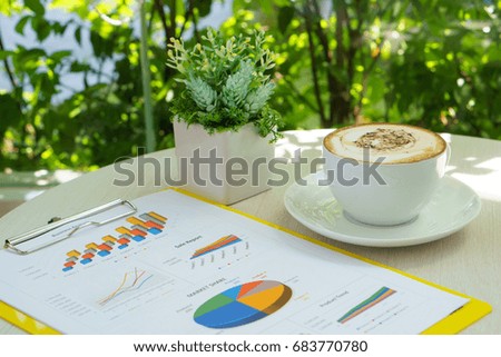 business analysis information document with latte art coffee and small plant on the table near the long modern windows glass during meeting in the cafe.
