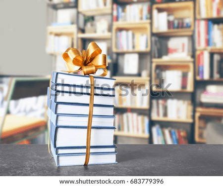 Books with ribbon bow as gift on table at library