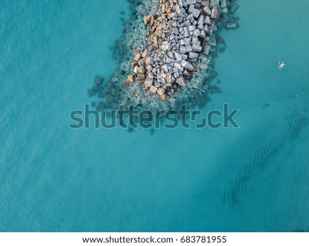 Aerial view of rocks on the sea. Overview of seabed seen from above, transparent water. Swimmers, bathers floating on the water
