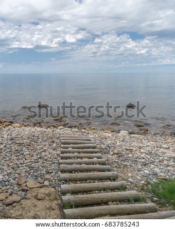 Log steps lead down to a stony Lake Superior beach on an idyllic day, in Pictured Rocks National Lakeshore, near Grand Marais, Michigan.