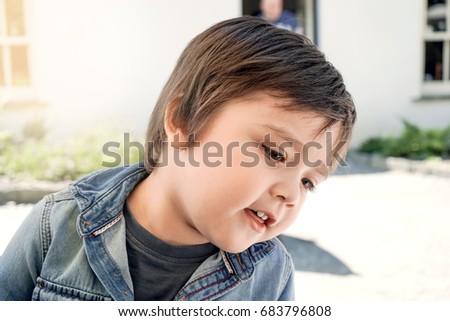 Portrait of happy cute little boy looking down to find some thing with a bit smiling on his face, beautiful face of caucasian kid wearing summer cloth                               