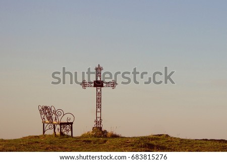Graveyard cross and bench in silhouette. copy space