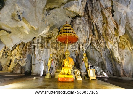 Old ancient buddha statue and stalagmite inside a cave