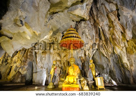 Old ancient buddha statue and stalagmite inside a cave