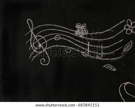 Cartoon music note draw by white chalk on blackboard in music classroom.