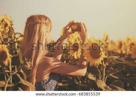 Woman enjoys photographing in beautiful sunflower field.Leisure time in nature with camera
Image is intentionally toned.
