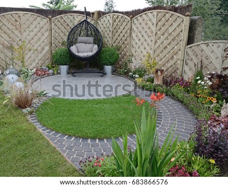 A garden design based on flowing curves around a patio area in a small urban garden Royalty-Free Stock Photo #683866576