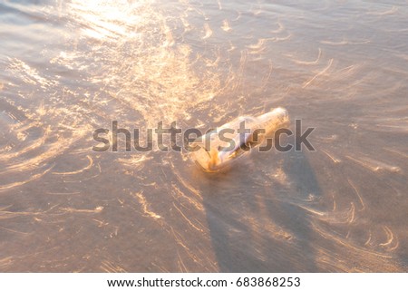 Message in a bottle on beach blurred object with abstract light from sunset 