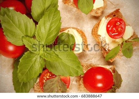 Cherry tomatoes lie on a table with basil and bread