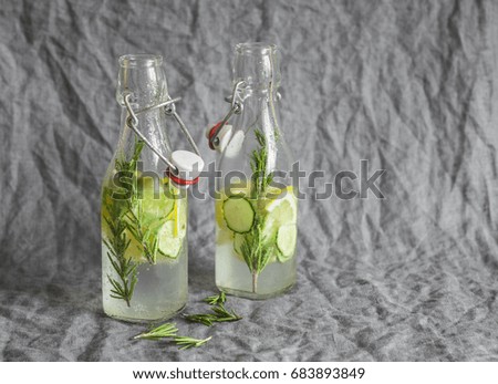 Rosemary, lemon, cucumber lemonade in vintage bottles on a grey background. Healthy refreshing drink