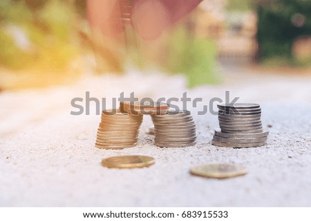 Stack of coins on cement floor over blurred image of green nature abstract background with vintage tone filter, Save money for growing your business, business and finance concept