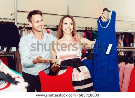 Young woman and man looking for new dress in showroom