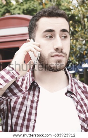 Portrait of young latin man talking on the phone. Outdoors. Urban scene.