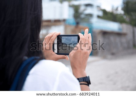 Woman traveler taking picture of the beach with cell phone on vacation
