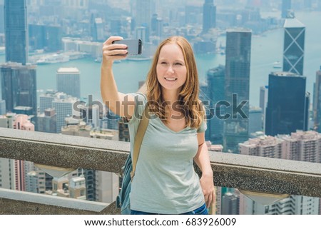 Hong Kong Victoria Peak woman taking selfie stick picture photo with smartphone enjoying view over Victoria Harbour. Viewing platform on top of Peak Tower, HK. Defocused background.Travel asia concept
