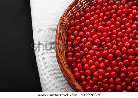 A brown wooden crate on a gray fabric and on a black background. Colourful red currant full of nutritious vitamins. Close-up ripe fresh currant. Delicious berries. 