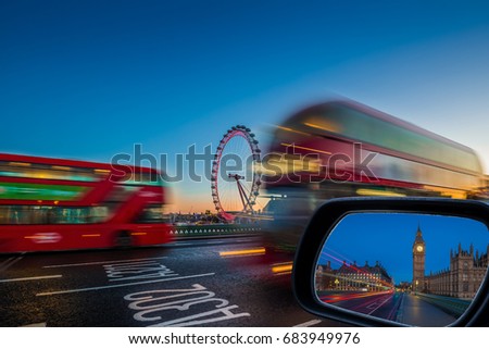 London, England - Traditional red double decker buses on the move on Westminster Bridge with Big Ben and Houses of Parliament at background at dusk