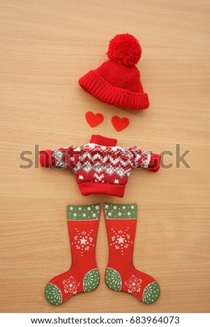 Knitted red warm cap, socks, pullover on wooden table texture background. two red heart - eyes sign, symbol, concept, idea. winter season. male, man figure. 