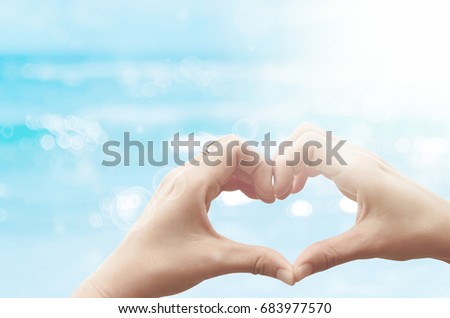 Female hands heart shape on nature bokeh sun light wave and blur tropical beach abstract background. Copy space of happy love travel and freedom in nature concept. Vintage tone color style.