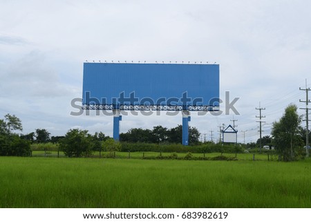 The blue billboards at field and electric post with sky near the road