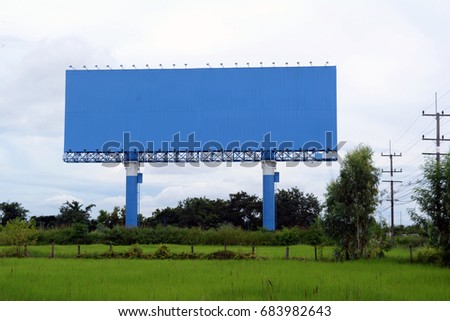 The blue billboards at field and electric post with sky near the road
