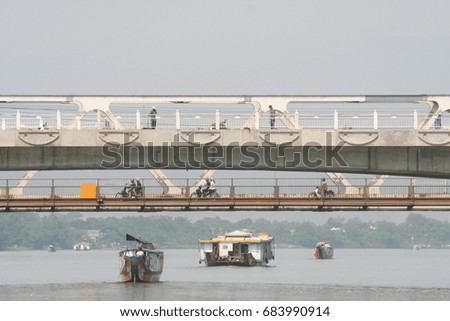 Hue, Vietnam river with boats, two bridges, pedestrians, motobykes in hot day
