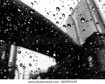 Emotional picture of rainy day in downtown, rain drip on a glass window with a background of Bangkok city