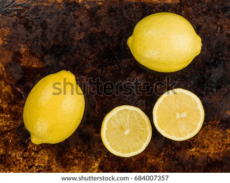 Fresh Ripe Whole And Half Juicy Citrus Lemons Against a Distressed Oven or Baking Tray, Flat Lay Composition With No People