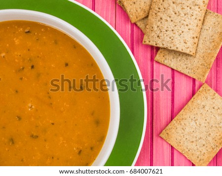 Bowl of Carrot and Coriander Soup Against a Pink Wooden Background