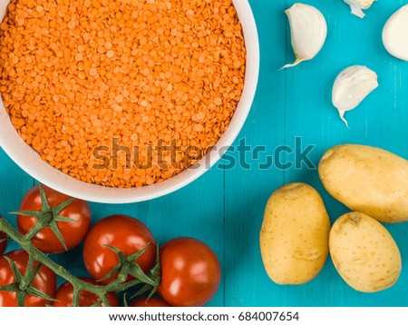 Bowl of Dry Uncooked Red Lentils Against a Blue Wooden Background