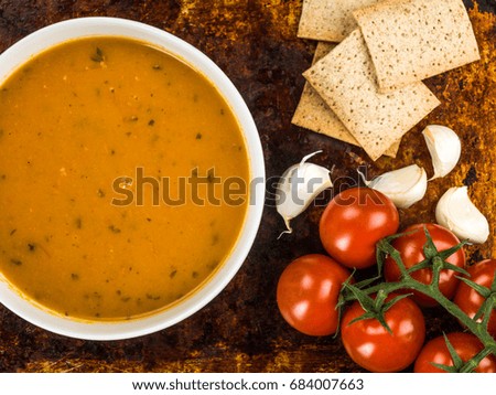 Bowl of Carrot and Coriander Soup Against a Distressed Burnt Oven or Baking Tray