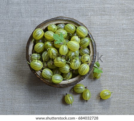 Raw green gooseberries with a vintage bowl on a vintage background. Top view