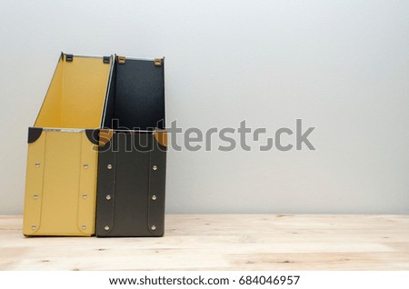 black and yellow blank office document file folders stack on wooden desk with white wall background