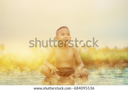 Asian Boy playing in water loosen hot looks happy, Before sunset background ,Thailand.