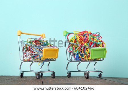 Shopping carts with rubber bands and paperclips on mint background