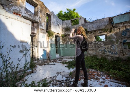 Young woman taking pictures of ruins abandoned buildings.