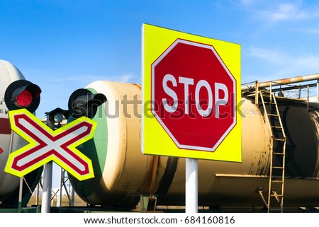 Traffic signs and traffic light on a railway crossing against the railway tank