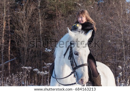 Nice girl and white horse in a forest in a winter day