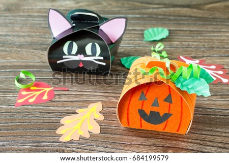 The child creates a gift box of a black cat of Halloween and a pumpkin of Halloween. Children's art project, craft for children. Craft for kids.