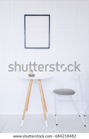 Corner of a kitchen with a table, gray chairs and a poster hanging on a light gray wall.