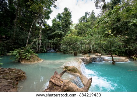 Wide angle picture of waterfall with blue water and tropical trees at Kuang Si Falls in Laos. National Park close to Luang Prabang,