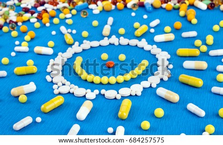 Many different colorful medication and pills from above in the shape of sun on a blue background