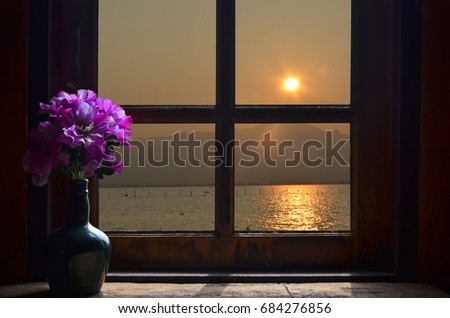 Violet vase in the sundown light through the window